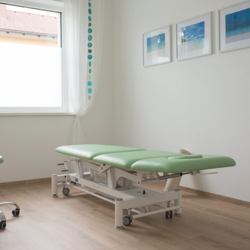 Therapieraum für Ergotherapie im Therapiezentrum Fixpunkt mit einer mint farbenen Behandlungsliege und Meerbilder an der Wand.